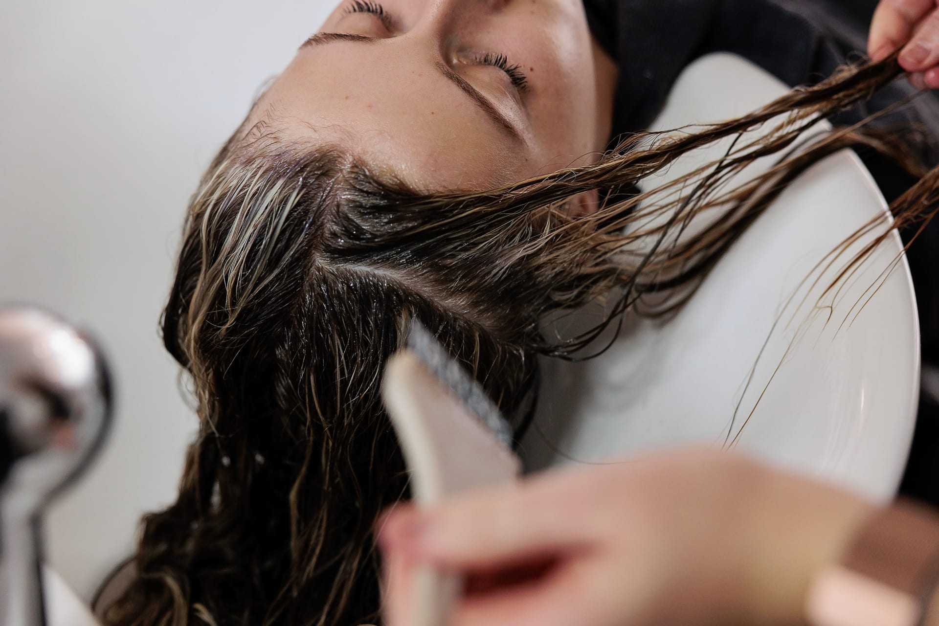 Client relaxing at the wash basin during an organic hair treatment at About Hair Mackay salon